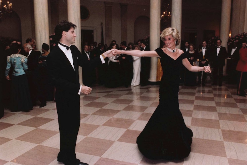 Princess Diana dances with John Travolta as people look on.