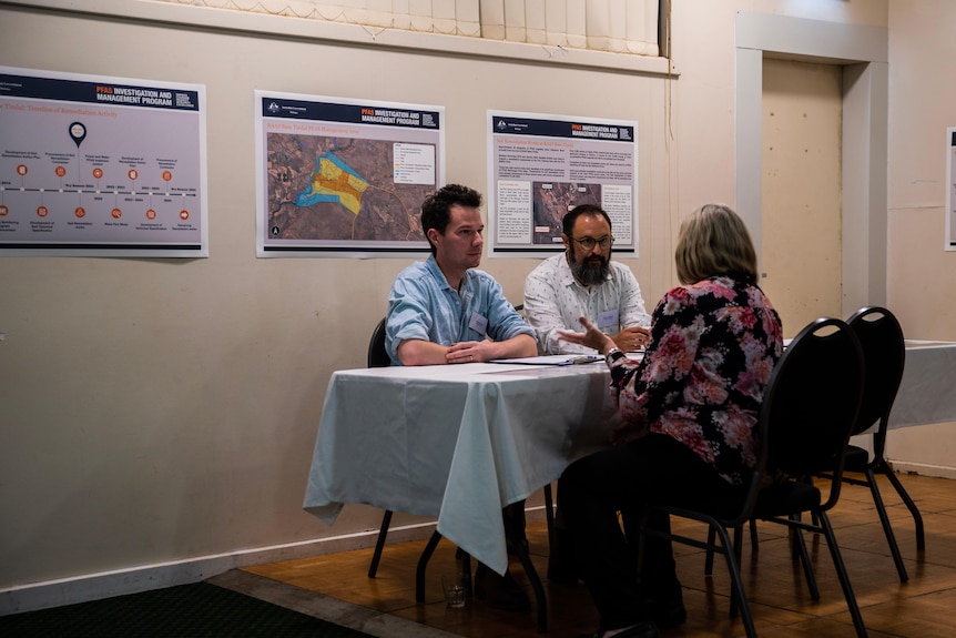 A woman sits at a table with two men. 