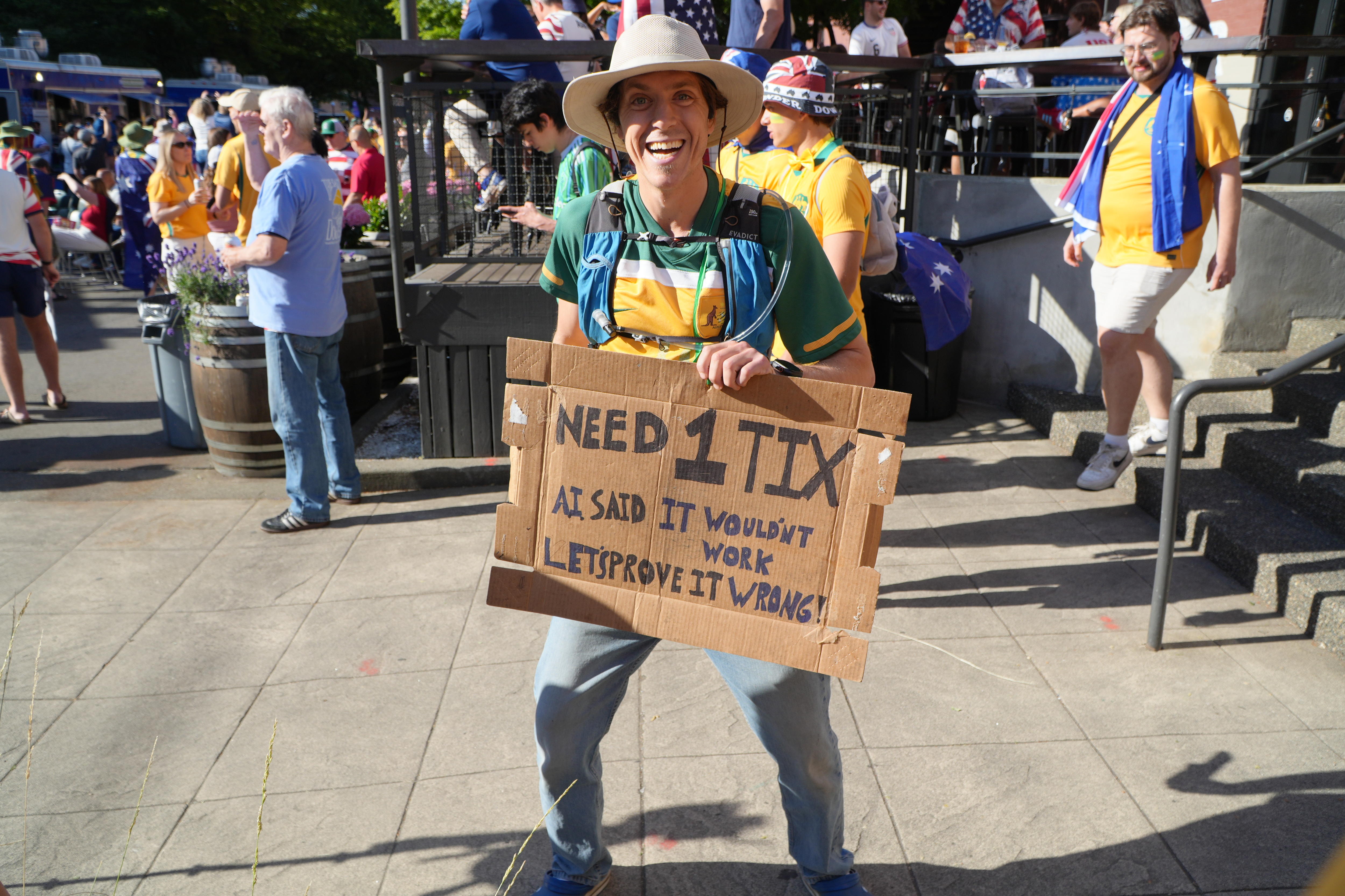 A man wears a sign asking for tickets to a soccer game