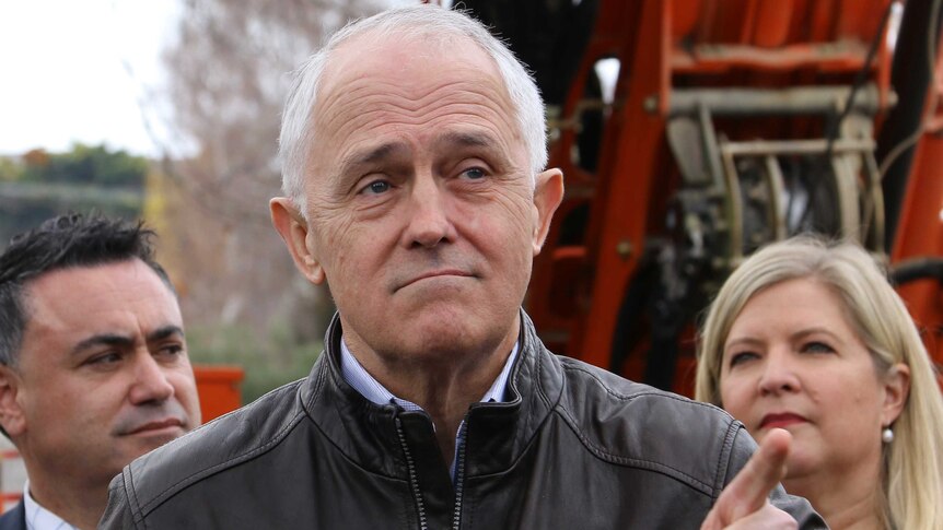 Prime Minister Malcolm Turnbull points while standing in front of machinery.