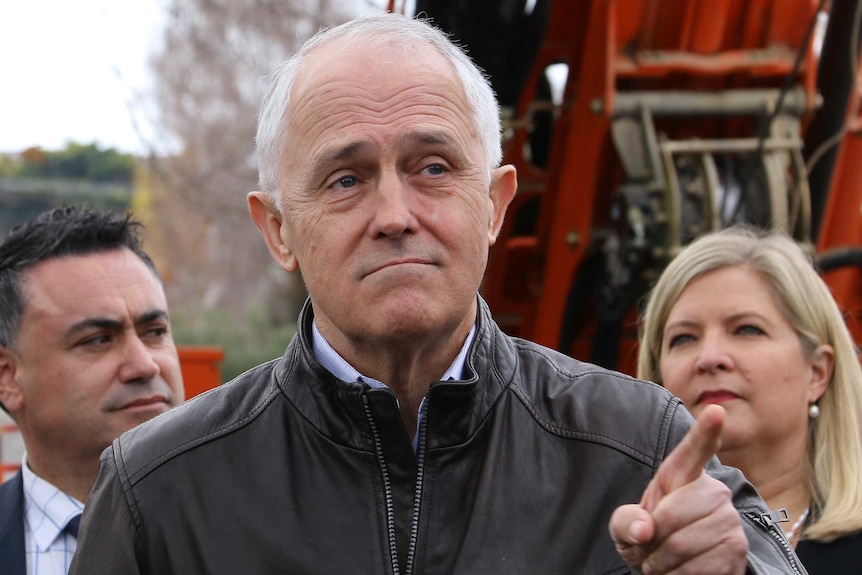 Prime Minister Malcolm Turnbull points while standing in front of machinery.