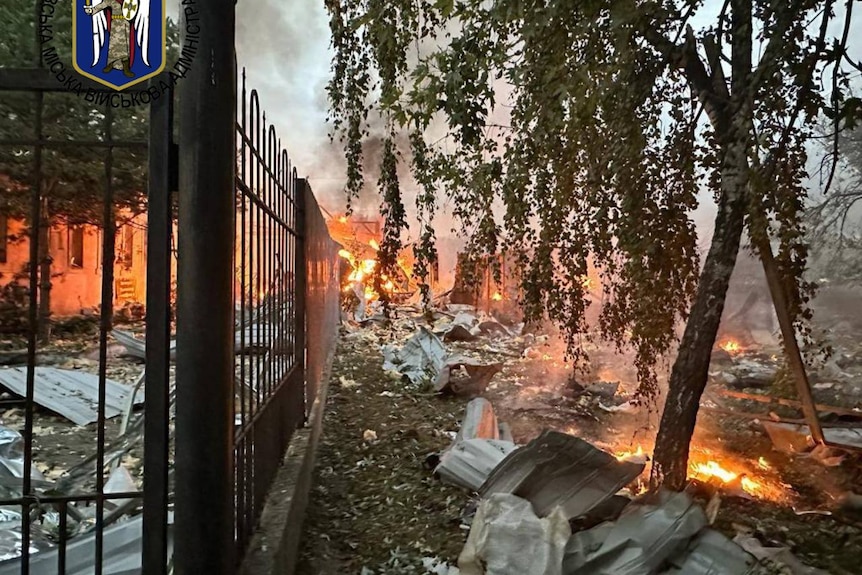 photo of fire and debris next to fence 