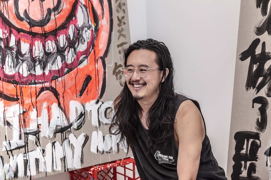 Artist Jason Phu in front of graffiti art