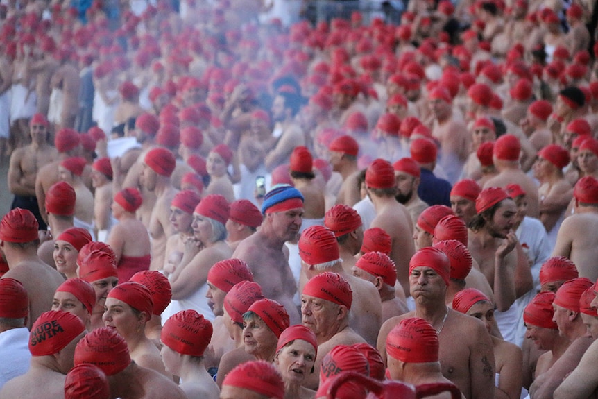 Red-capped swimmers gathered on beach.
