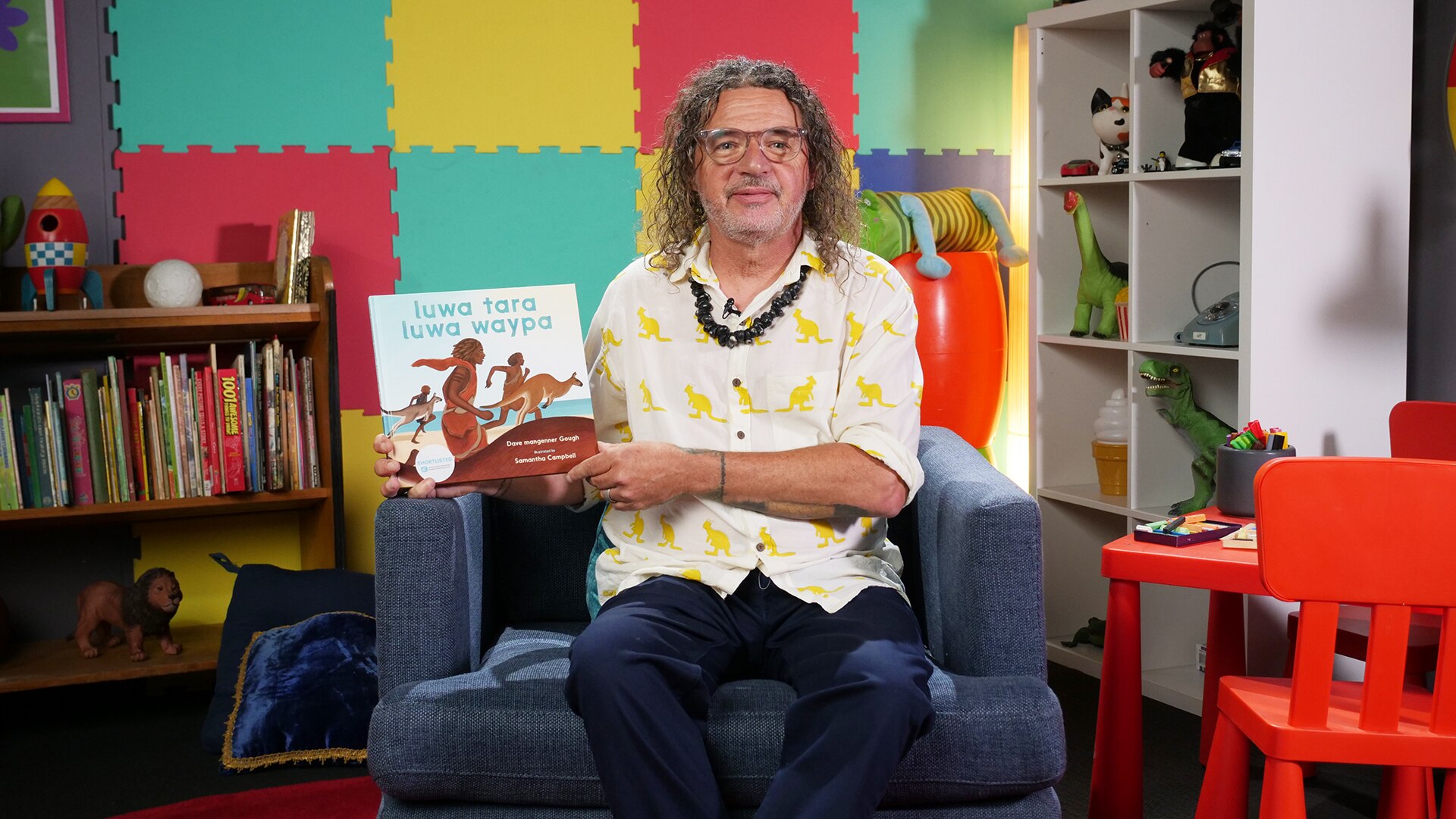 Dave mangenner Gough holds up story book, luwa tara luwa waypa