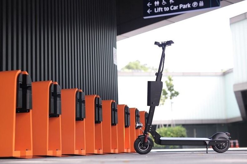 An electric scooter parked near a charge station