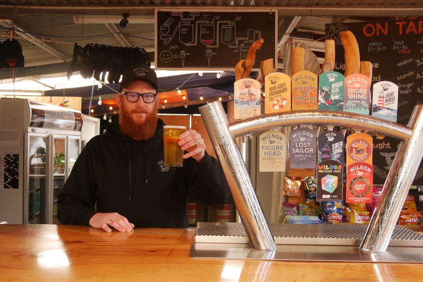 Homme derrière le bar au pub avec une bière