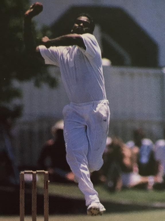 Коренной мужчина в белом играет в крикет 