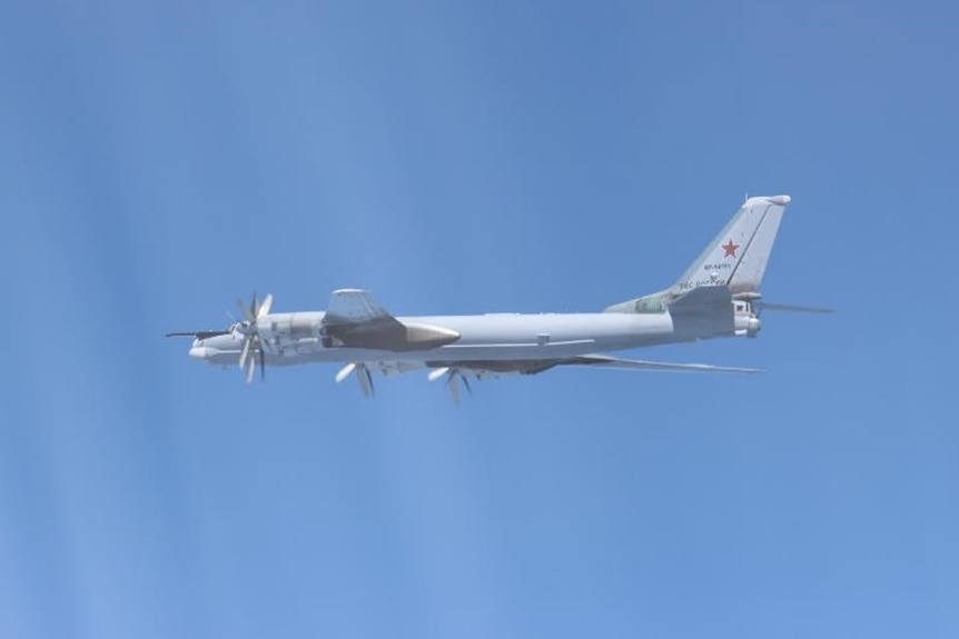 A Russian TU-95 bomber flies through a clear sky.