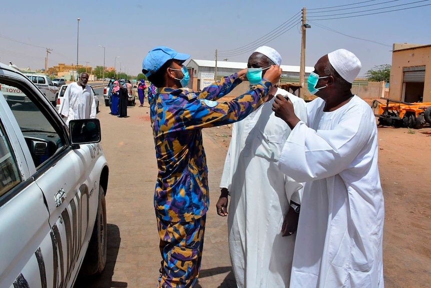 Medical workers don masks near a car