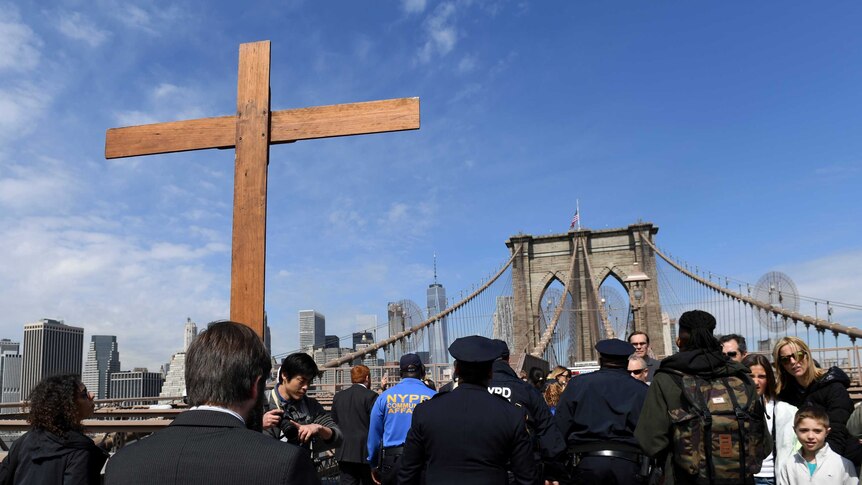 Vitaly Kuzmin holds a cross as he leads the Way of the Cross procession across the Brooklyn Bridge with NYPD officers