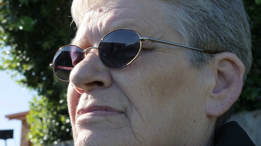 Close shot of a woman wearing sunglasses looking off into the distance on a sunny day