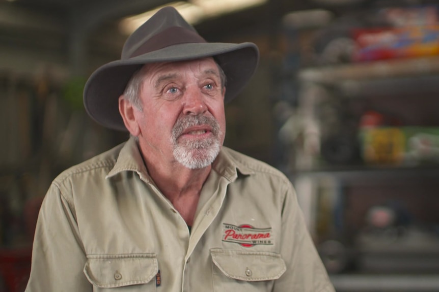 A an wearing a khaki button up shirt and a brown hat.