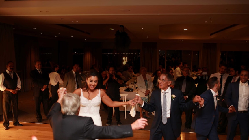 Eleni Kallianiotis dances with her dad and family friends at her Melbourne wedding.