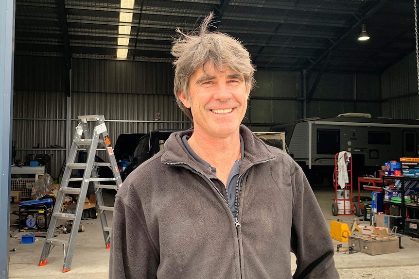 Smiling photo of Ken Jeffery standing in front of a shed at Moruya in south-east New South Wales.