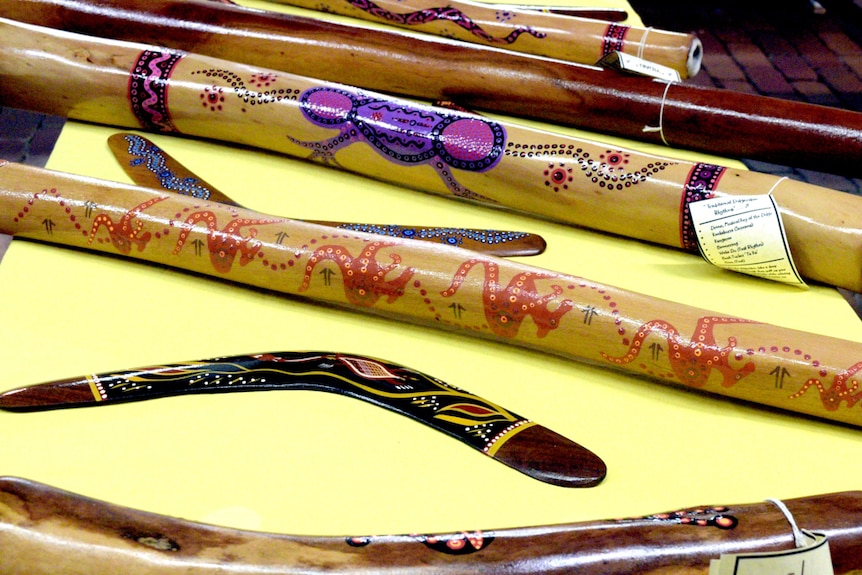 Didgeridoos and boomerangs rest on a yellow counter.