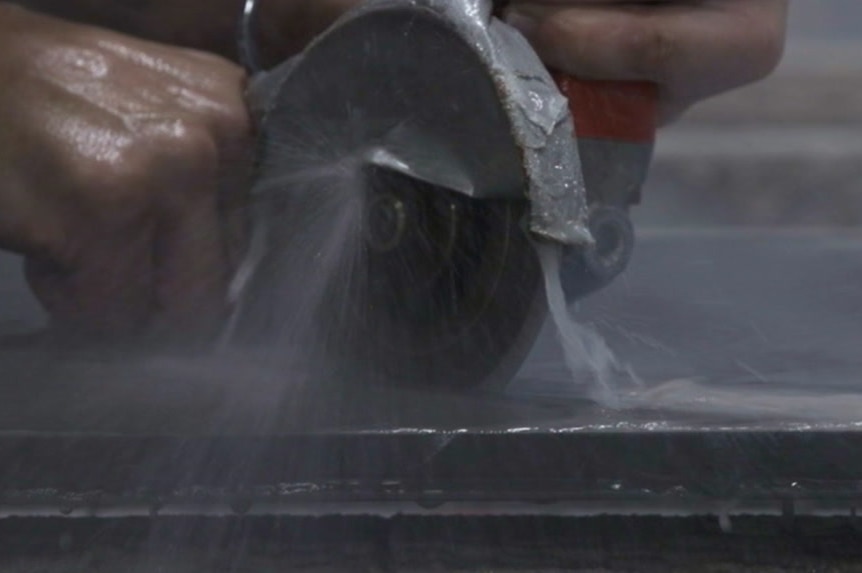 A person wet-cutting stone