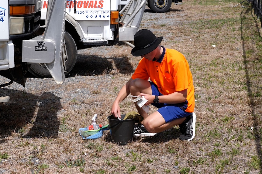 Nathan kneeling on the ground, taking things in and out of a bucket. 