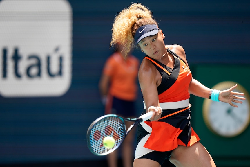 Naomi Osaka looks down at her racquet as she hits a forehand return.