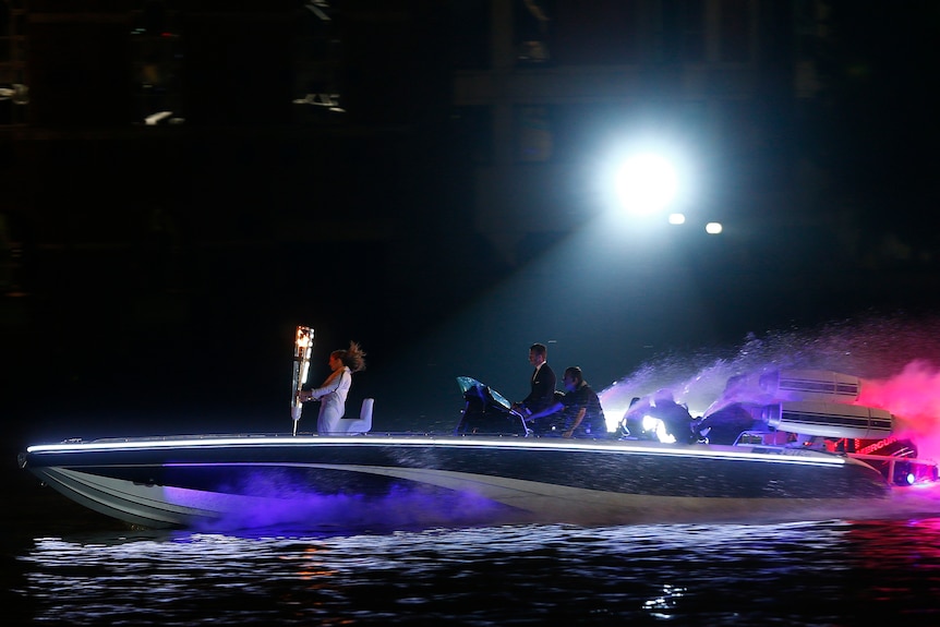 David Beckham heads down the Thames in a speedboat, carrying the Olympic flame.