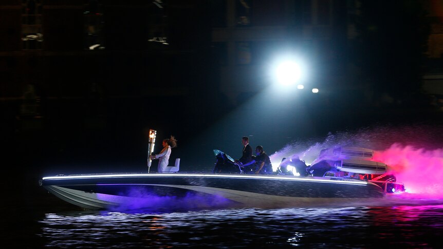 David Beckham drives a powerboat with the Olympic torch aboard during the opening ceremony.