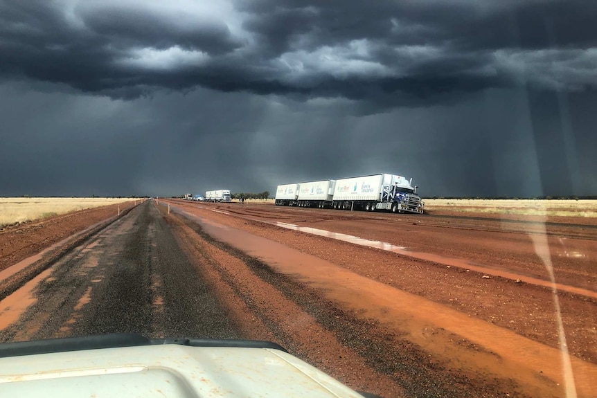 a truck bogged on the side of the road under stormy skies.