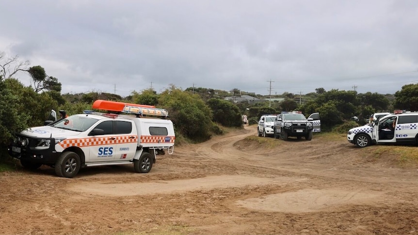 Police and SES vehicles at a beach.