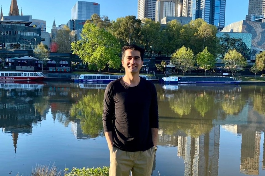 A man smiling at the camera in front of the Yarra River.