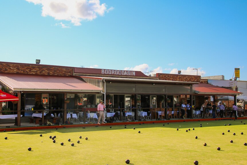A man watching a lawn bowls game.