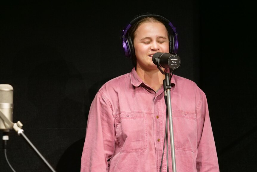 A person with a red shirt singing into a microphone. 