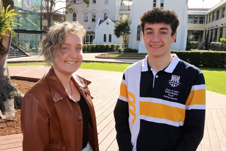 CourtneyJade Goodman wearing a brown jacket and Nathan Wrigley wearing a 'Class of 2021 College Captain' jersey at school.