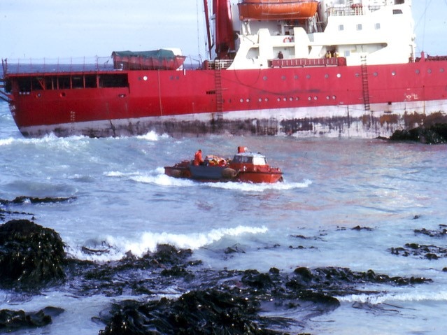 A large vessel washed up on rocks.