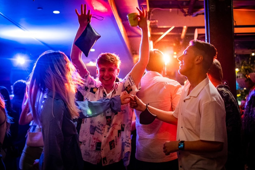 a young man raising his hands as a couple dance