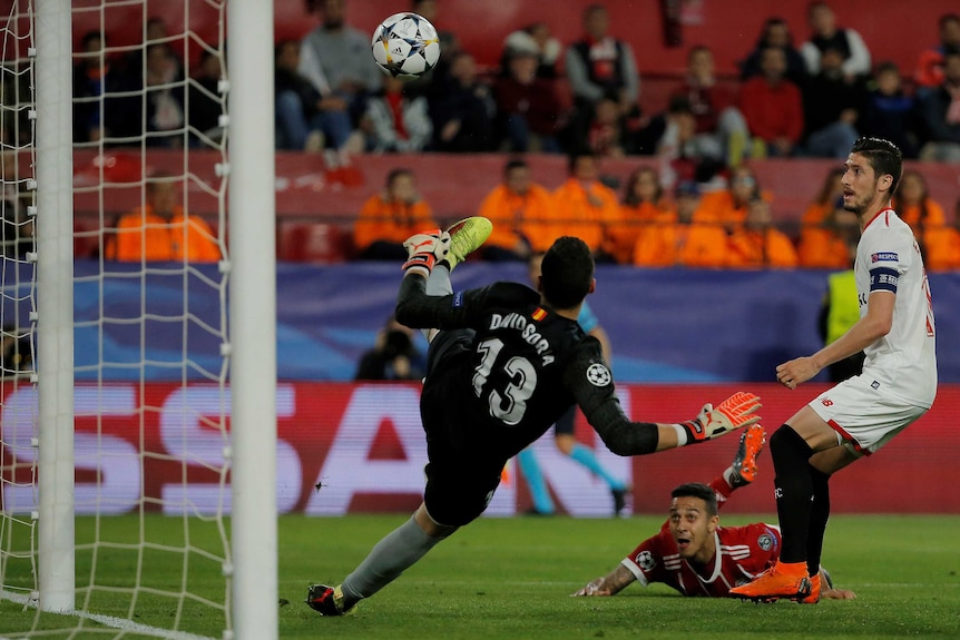 A diving Bayern Munich player heads the ball past a goalkeeper.