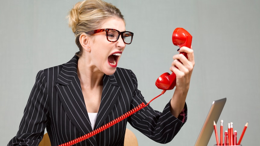 A woman at work yells angrily into a phone