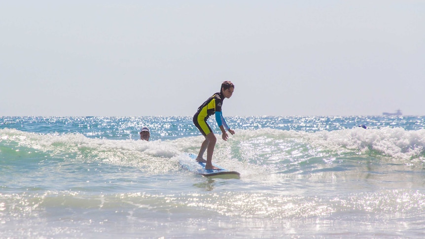 A boy surfs on a blue board.