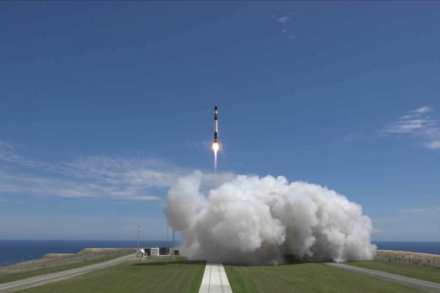 A rocket going up into the sky above a huge cloud