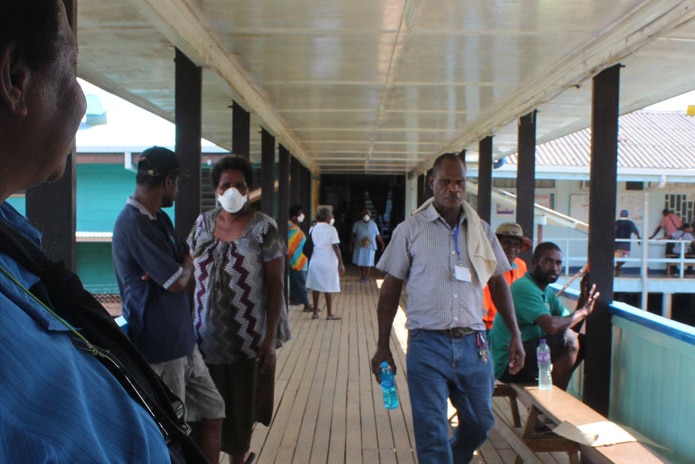 People stand in the corridor outside the hospital building.