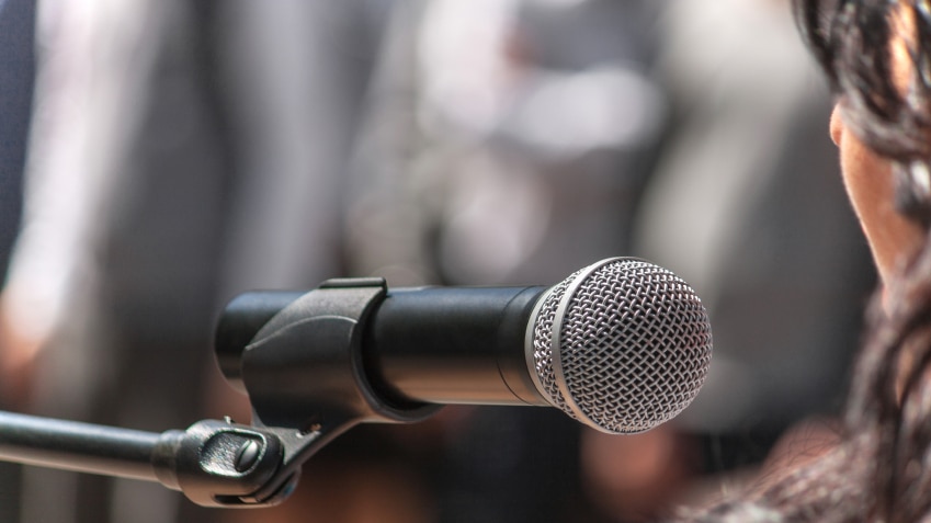 A woman talking into a microphone at an event.