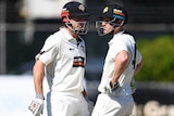 WA batsmen Shaun Marsh (left) and Cameron Bancroft speak to each other wearing cricket whites and helmets during a game.