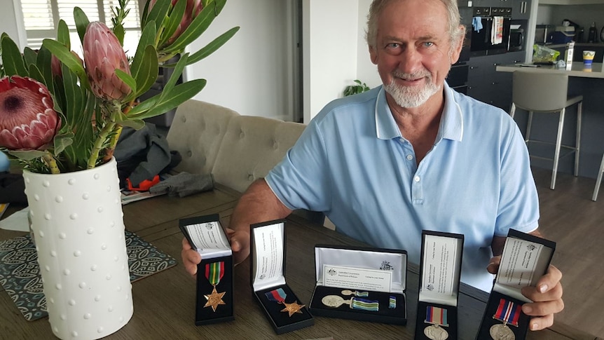 Robert Cooper sitting at a table with five war service medals 