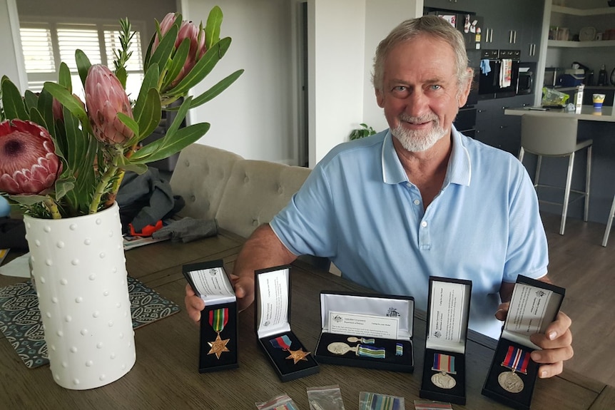 Robert Cooper sitting at a table with five war service medals 