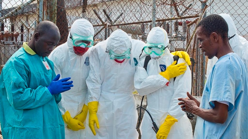 Red Cross workers pray before removing a body in Liberia