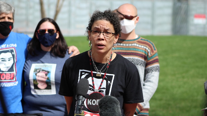 A woman with glasses speaks into a microphone