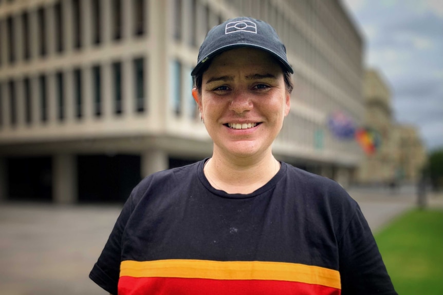 Meriki Onus wearing a cap with an outline of the Aboriginal flag, and a shirt with "Always Was, Always Will Be".