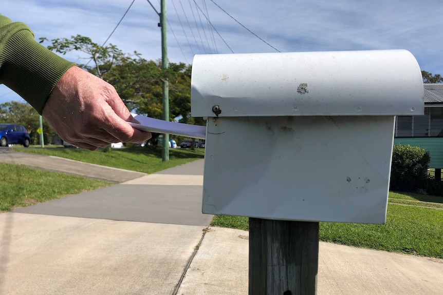 Hand putting paper in letterbox