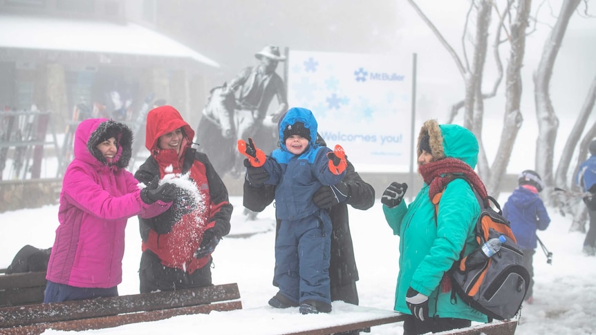 Women and a young child playing in the snow.