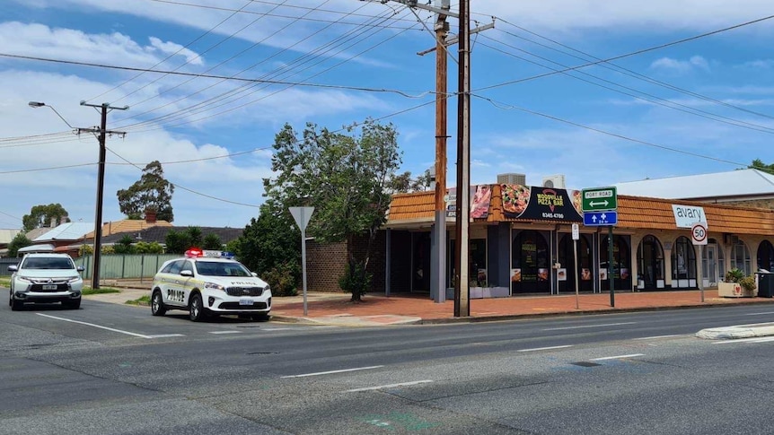 A pizza restaurant on a main road with a police four-wheel drive next to it