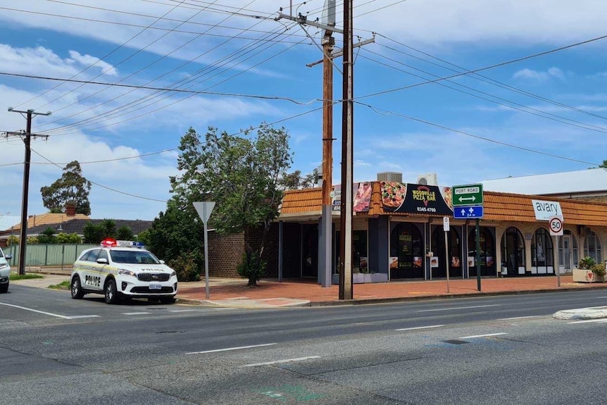 A pizza restaurant on a main road with a police four-wheel drive next to it