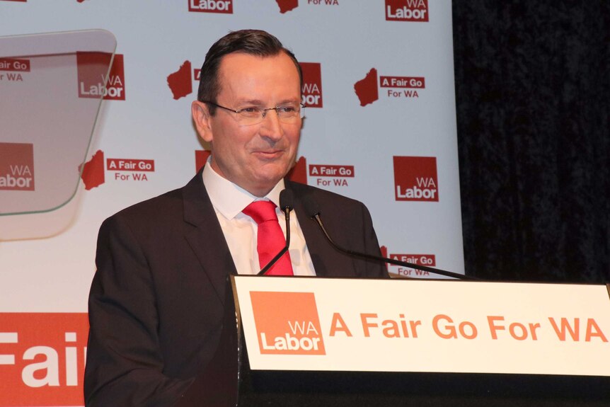 Mark McGowan stands at a podium with Labor signs around him.